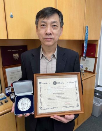 A picture of Dr. Lim holding  the Reddy Medal and certificate